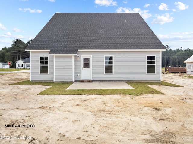 back of property with a patio area and roof with shingles