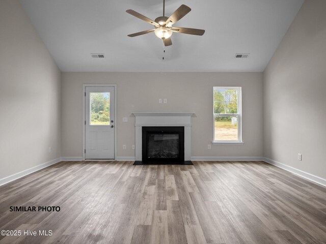 unfurnished living room featuring a fireplace with flush hearth, wood finished floors, and visible vents