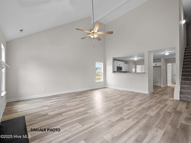 unfurnished living room with stairway, light wood-style flooring, lofted ceiling with beams, and visible vents