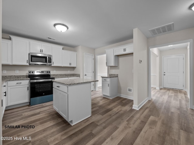 kitchen with stainless steel appliances, wood finished floors, visible vents, and white cabinets