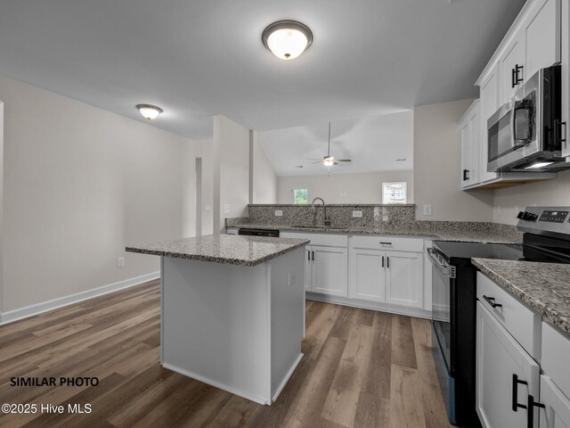 kitchen featuring stainless steel microwave, light wood-style flooring, electric stove, and a sink