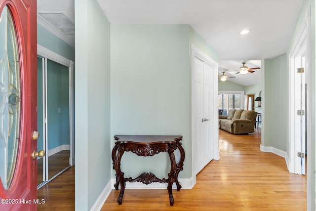 corridor with vaulted ceiling, baseboards, visible vents, and light wood finished floors