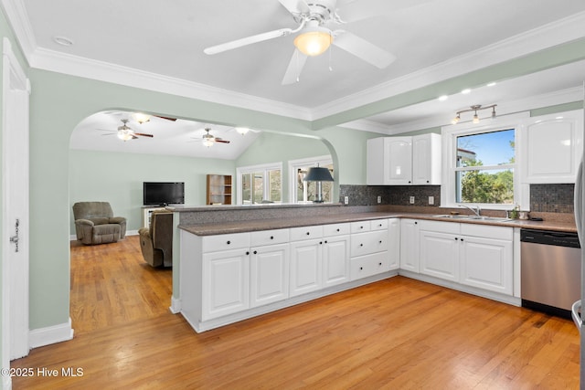 kitchen with a sink, arched walkways, light wood-style floors, and dishwasher