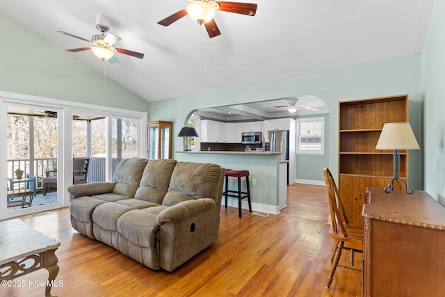 living room with lofted ceiling, light wood-style floors, baseboards, and ceiling fan