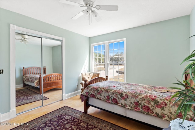 bedroom with a closet, a ceiling fan, baseboards, and wood finished floors