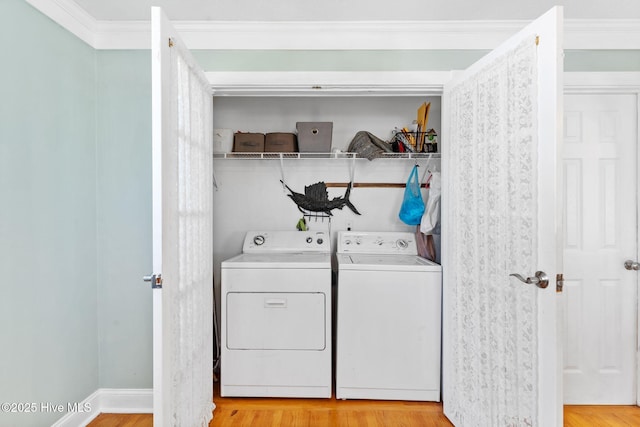 washroom featuring light wood finished floors, crown molding, baseboards, laundry area, and separate washer and dryer