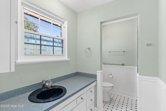 bathroom featuring vanity, toilet, and wainscoting