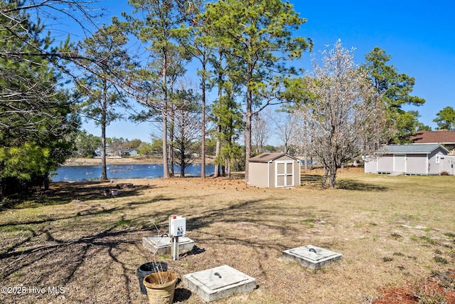 view of yard featuring a storage shed, an outdoor structure, and a water view