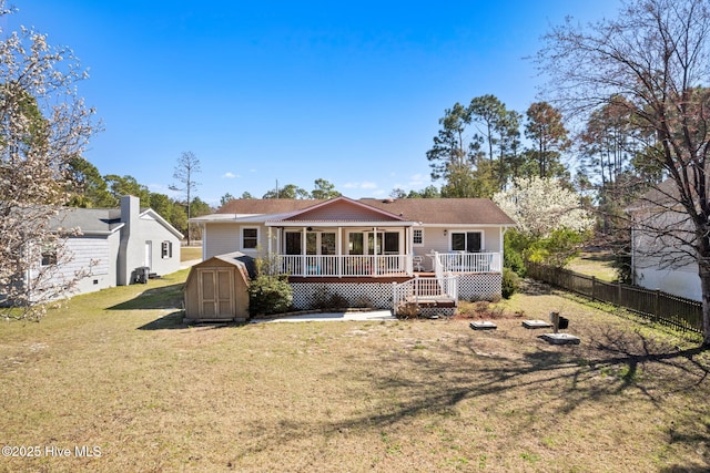 rear view of property featuring a storage unit, an outbuilding, fence, a yard, and a wooden deck