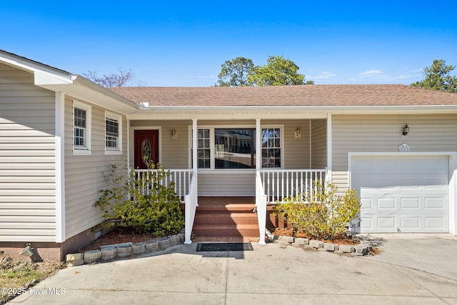 view of exterior entry featuring a porch, concrete driveway, a garage, and a shingled roof