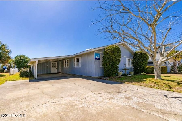 ranch-style home with an attached carport, concrete driveway, and a front yard