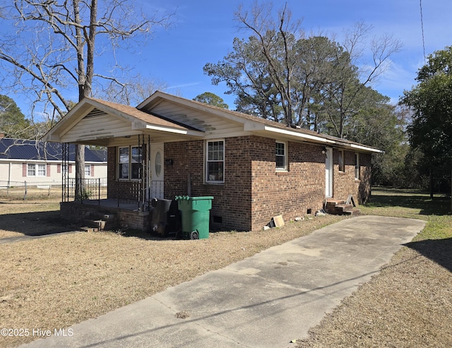 view of property exterior with covered porch, concrete driveway, crawl space, and brick siding