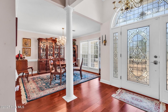 foyer entrance featuring crown molding, baseboards, a chandelier, decorative columns, and wood finished floors