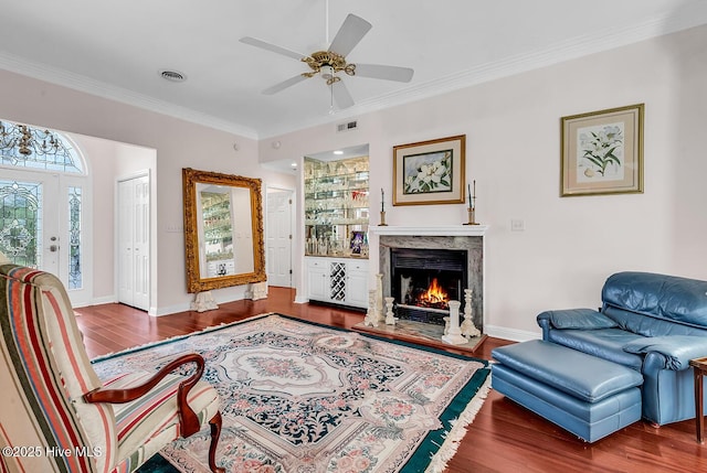 living area featuring visible vents, baseboards, wood finished floors, and crown molding