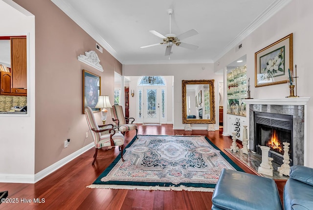 sitting room featuring wood finished floors, ornamental molding, and a high end fireplace