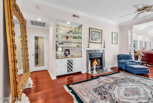 living room with visible vents, dark wood-type flooring, crown molding, and decorative columns