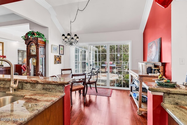 dining area featuring dark wood-type flooring, an inviting chandelier, crown molding, and vaulted ceiling