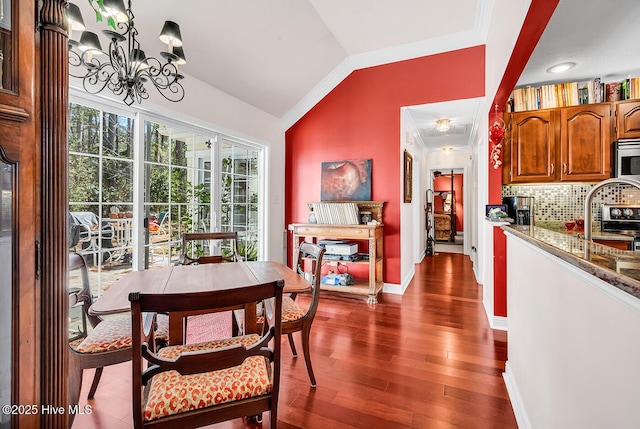 dining room with baseboards, lofted ceiling, an inviting chandelier, and dark wood finished floors