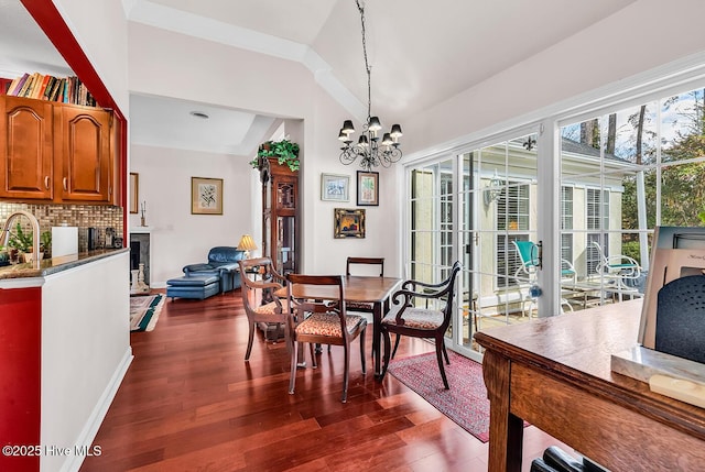 dining space with crown molding, baseboards, a chandelier, vaulted ceiling, and dark wood-style flooring