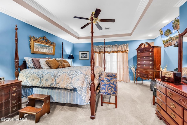 carpeted bedroom with a tray ceiling, a ceiling fan, visible vents, and crown molding