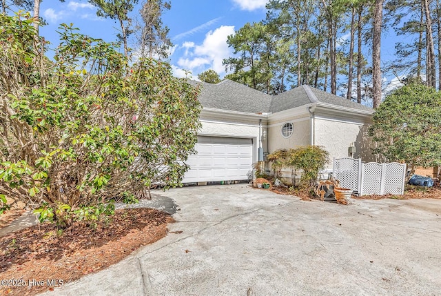 view of property exterior featuring a shingled roof, a garage, driveway, and stucco siding