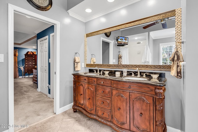 ensuite bathroom featuring a sink, baseboards, and ornamental molding