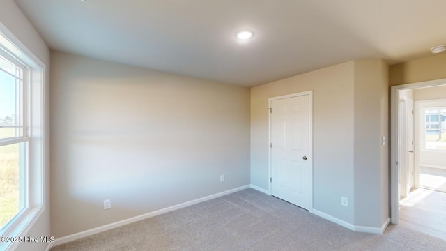 unfurnished bedroom featuring light carpet and baseboards