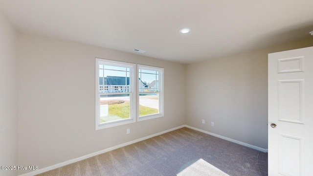 carpeted spare room with visible vents and baseboards