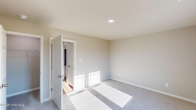 unfurnished bedroom with a closet, light colored carpet, and baseboards