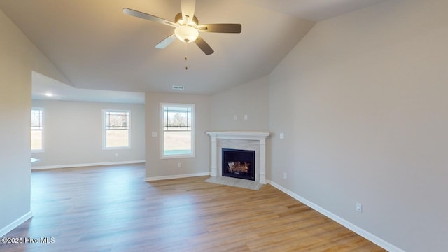 unfurnished living room featuring light wood-type flooring, lofted ceiling, baseboards, and a fireplace