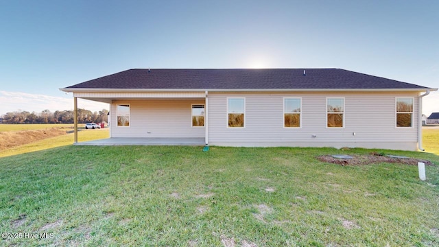 rear view of property featuring a patio, a lawn, and a shingled roof