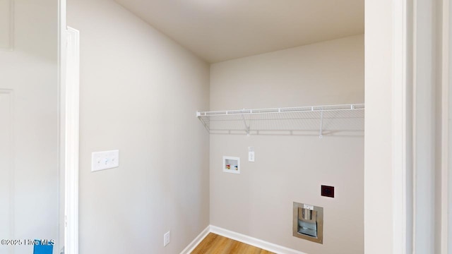 laundry room with hookup for a washing machine, heating unit, baseboards, laundry area, and light wood-style floors