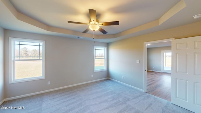 spare room featuring plenty of natural light, a tray ceiling, and carpet floors