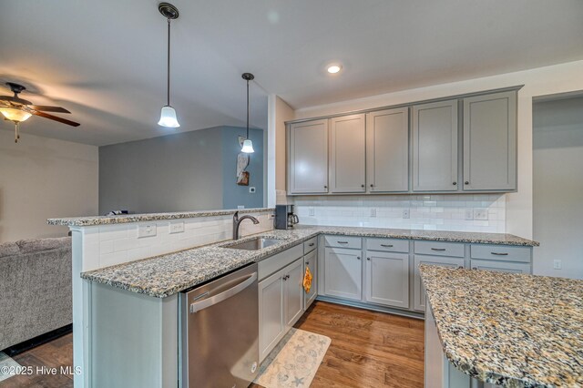 kitchen with a sink, stainless steel dishwasher, open floor plan, a peninsula, and dark wood-style flooring