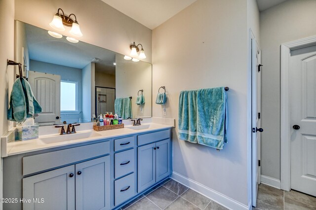 full bath featuring a sink, baseboards, double vanity, and tile patterned floors