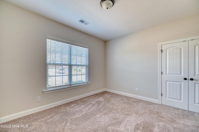 carpeted empty room featuring visible vents and baseboards