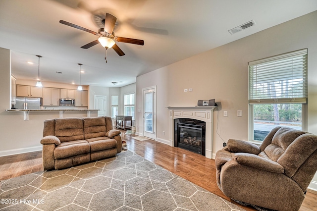 living room with a wealth of natural light, visible vents, and light wood finished floors