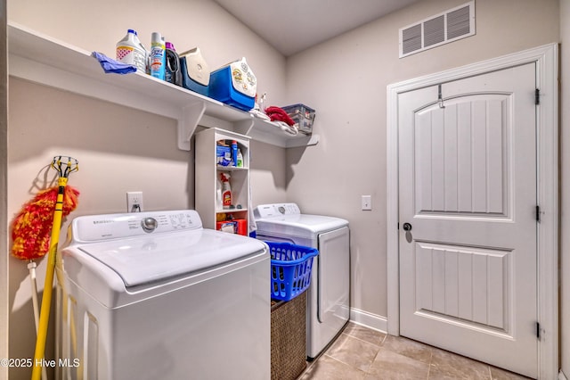 washroom featuring baseboards, visible vents, laundry area, light tile patterned flooring, and washer and clothes dryer