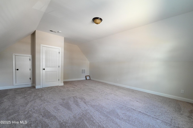 additional living space featuring visible vents, carpet flooring, baseboards, and lofted ceiling