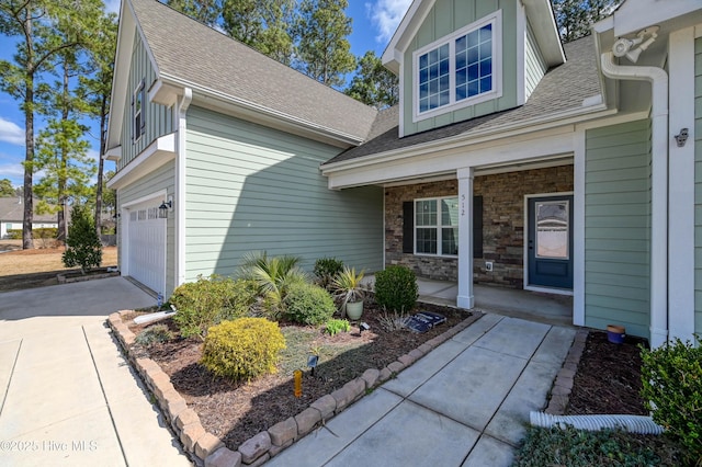 entrance to property with board and batten siding, a shingled roof, a porch, a garage, and stone siding