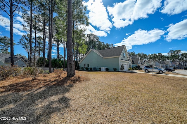 view of yard featuring a garage, a residential view, and concrete driveway