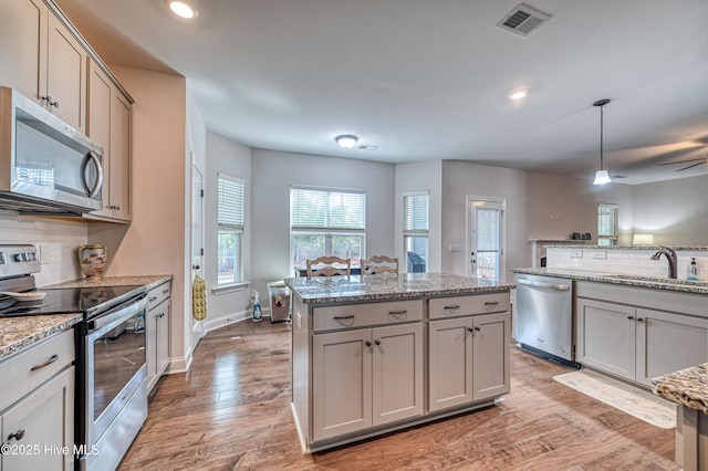 kitchen with tasteful backsplash, visible vents, gray cabinetry, appliances with stainless steel finishes, and a sink