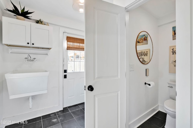 bathroom featuring tile patterned floors, toilet, baseboards, and a sink