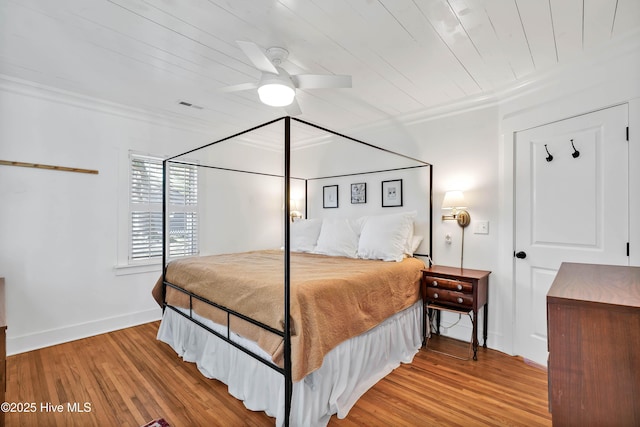 bedroom featuring visible vents, ornamental molding, baseboards, and wood finished floors