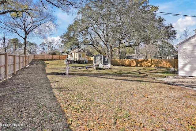 view of yard featuring an outbuilding, a fenced backyard, and a shed