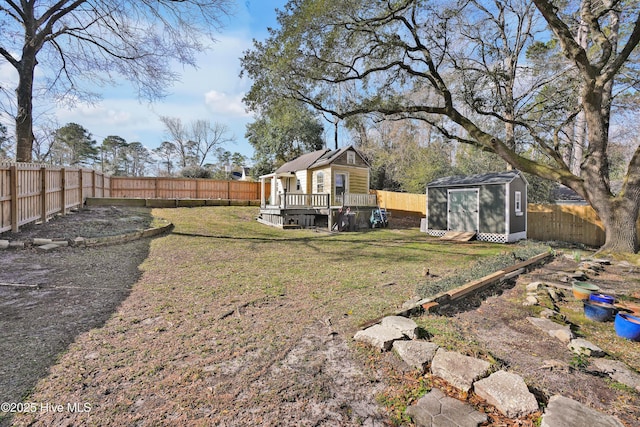 view of yard featuring a deck, an outbuilding, a fenced backyard, and a storage shed