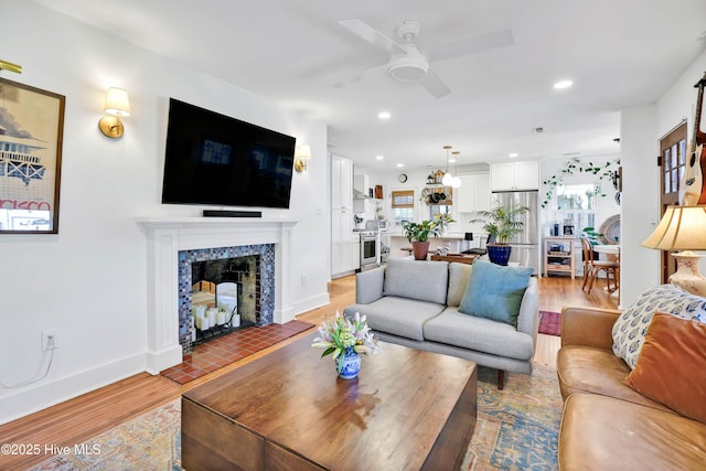 living area featuring a high end fireplace, recessed lighting, light wood finished floors, and a ceiling fan