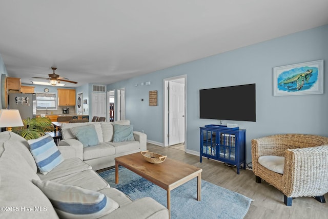 living room featuring visible vents, baseboards, light wood-style floors, and a ceiling fan