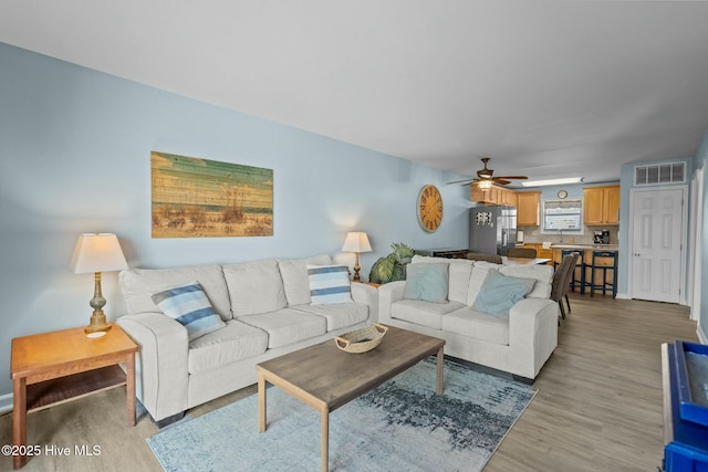 living area with visible vents, light wood-style flooring, and a ceiling fan