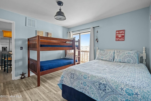 bedroom featuring visible vents, wood finished floors, baseboards, and stainless steel fridge with ice dispenser